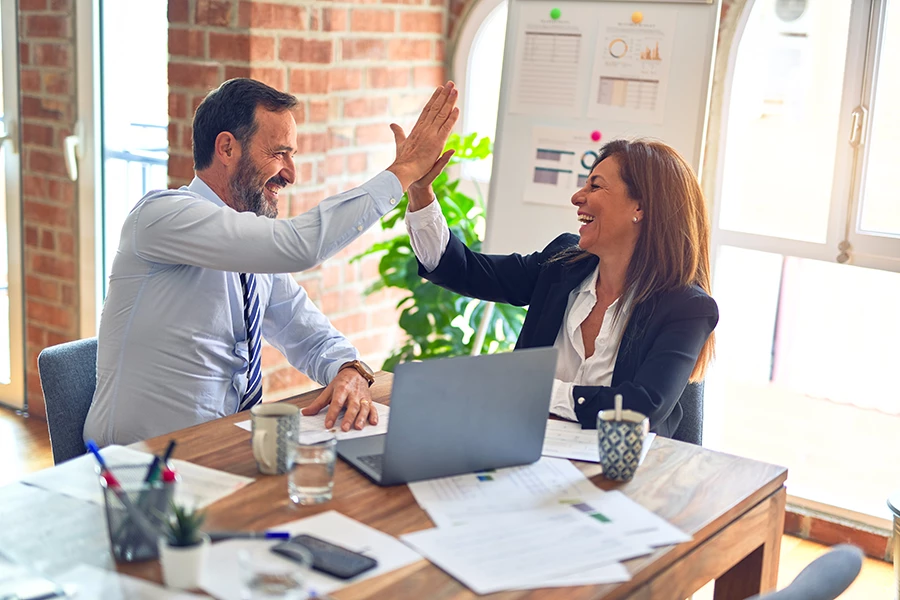 two people at a desk high-fiving