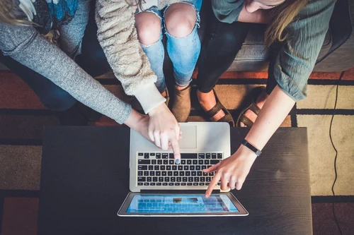 three women sharing a laptop